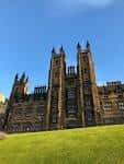 Fachada gótica de los torres de la Universidad de Edimburgo bajo un cielo azul despejado
