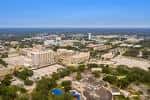 Vista aérea panorámica del campus universitario con edificios y zonas verdes bajo cielo despejado