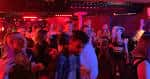 Interior del local durante un evento nocturno, con iluminación roja y público asistiendo a una actuación o fiesta