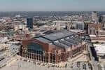 Vista aérea del Lucas Oil Stadium en Indianápolis, mostrando su estructura exterior y entorno urbano