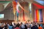 Interior del templo durante un evento con banderas arcoíris y congregación reunida