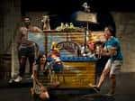 Escena de una obra de teatro con actores y decorado colorido