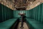 Sala íntima con bancos tapizados en verde y techo de piedra abovedado