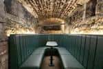 Espacio subterráneo con asientos en U y paredes de piedra iluminadas