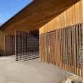 Detalle arquitectónico de la entrada principal con revestimiento de listones de madera y puerta metálica