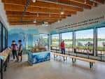 Interior del centro con techo de vigas de madera, grandes ventanales y exhibiciones interactivas para visitantes