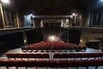 Interior del auditorio principal con butacas rojas dispuestas en gradas y escenario iluminado