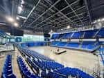 Interior del pabellón deportivo con gradas azules y cancha central