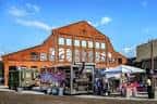Fachada exterior del edificio Pullman Yards con puestos de mercado al aire libre