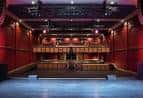 Interior del auditorio con escenario y butacas rojas