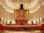 Interior del auditorio con órgano en el escenario y butacas rojas