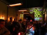 Interior del bar con ambiente festivo y cartel de 'The Others' proyectado