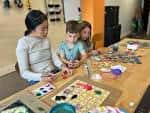 Adulto y niños colaborando en un proyecto manual en la mesa de trabajo