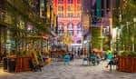 Espacio exterior iluminado con mesas y vegetación en Market East