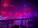 Interior del club con iluminación de neón y ambiente festivo