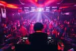 DJ actuando frente a una multitud bajo luces rojas