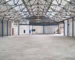 Espacio interior amplio y vacío con techo de estructura metálica, ideal para eventos