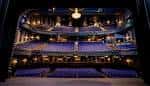 Interior del auditorio con butacas azules, balcones curvos e iluminación cálida ideal para eventos