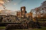 Vista panorámica de Kirkstall Abbey al atardecer con cielo dramático