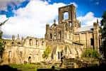 Fachada principal de las ruinas de la abadía bajo un cielo azul con nubes