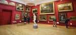 Sala de exposiciones con paredes rojas y obras de arte enmarcadas
