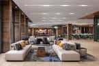 Área de lounge interior con sofás blancos, alfombra decorativa y iluminación ambiental