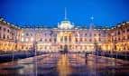 Somerset House iluminado por la noche con reflejos en el suelo mojado, ambiente festivo