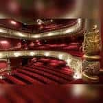 Interior del auditorio con butacas rojas, balcones ornamentados y escenario iluminado