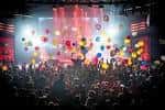 Evento festivo con globos cayendo sobre el público