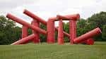 Estructura roja abstracta en medio de un prado verde