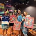 Grupo de personas mostrando sus obras de arte en un evento de Pinot's Palette