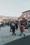 Plaza del mercado con gente transitando entre los puestos bajo toldos