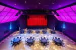Interior del auditorio configurado para evento con mesas y luces de ambiente