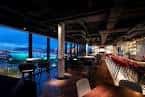 Interior del bar con vistas nocturnas a la ciudad desde grandes ventanales