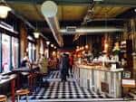 Interior del Boston Tea Party en Corporation Street con decoración industrial y suelo a cuadros