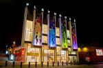 Vista nocturna de la fachada del Leeds Playhouse con iluminación y banderines
