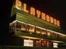 Fachada exterior del teatro por la noche con letrero luminoso 'PLAYHOUSE'