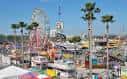 Área de atracciones con noria y palmeras bajo cielo azul