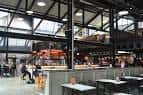 Interior del Cambridge Street Collective con estructura industrial y mesas de comedor