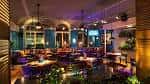 Sala de eventos con mesas, iluminación ambiental y decoración tropical