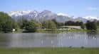 Vista panorámica del lago de Sugar House Park con montañas nevadas al fondo