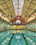 Piscina cubierta decorada con banderines festivos bajo una estructura arquitectónica histórica