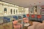 Vista del interior moderno con barra y sillones frente a la fachada histórica de George Square