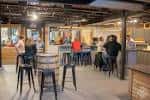 Interior del bar con clientes sentados en taburetes junto al mostrador