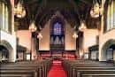 Interior de la iglesia con pasillo rojo y órgano al fondo
