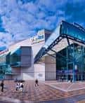 Fachada principal del ICC Birmingham bajo cielo azul con personas caminando frente al edificio