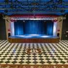 Interior del auditorio con escenario y cortinas azules