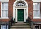 Entrada principal del edificio con puerta verde y escalinata de piedra