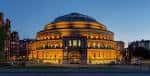 Vista nocturna del Royal Albert Hall con fachada iluminada en tonos dorados
