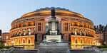 Fachada frontal del Royal Albert Hall al atardecer con estatua central y escalinatas